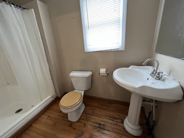 full bath with baseboards, toilet, wood finished floors, and a shower stall