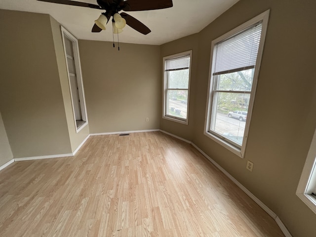 empty room with visible vents, light wood-style flooring, baseboards, and ceiling fan