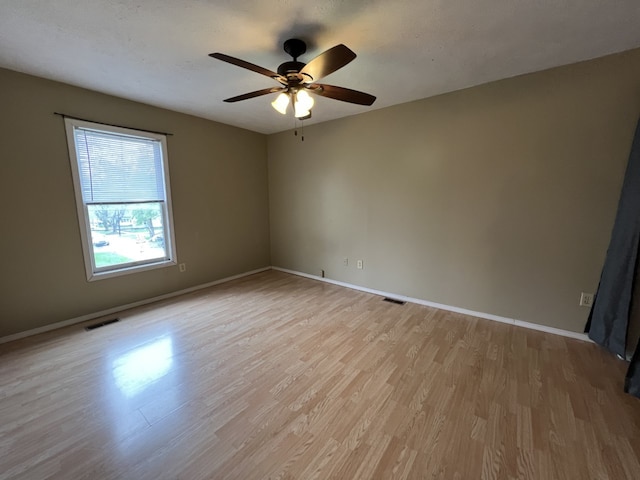 unfurnished room featuring light wood-style flooring, a ceiling fan, visible vents, and baseboards