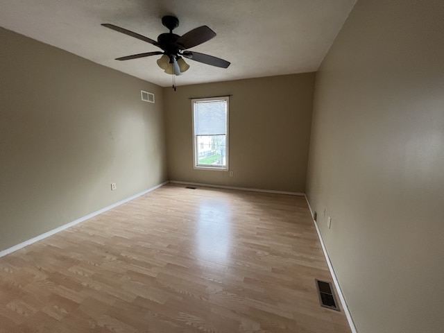 spare room with visible vents, ceiling fan, baseboards, and light wood-style floors