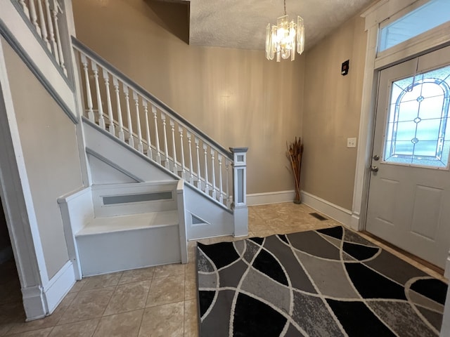 entryway featuring stairway, a textured ceiling, baseboards, and an inviting chandelier