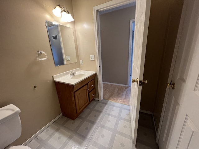 half bathroom with vanity, tile patterned floors, toilet, and baseboards