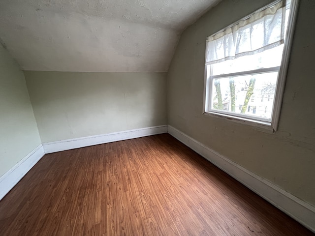 bonus room featuring vaulted ceiling, wood finished floors, baseboards, and a textured ceiling