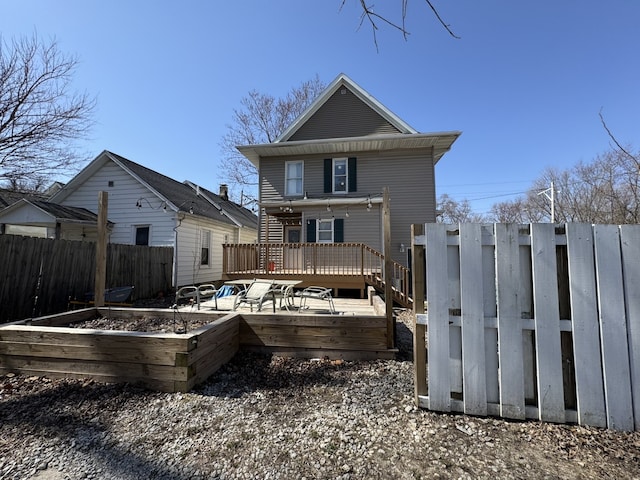 back of house with a deck, a garden, and fence