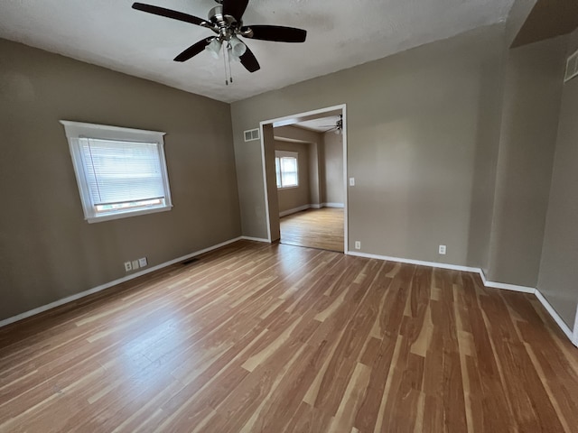 empty room with visible vents, baseboards, a ceiling fan, and wood finished floors