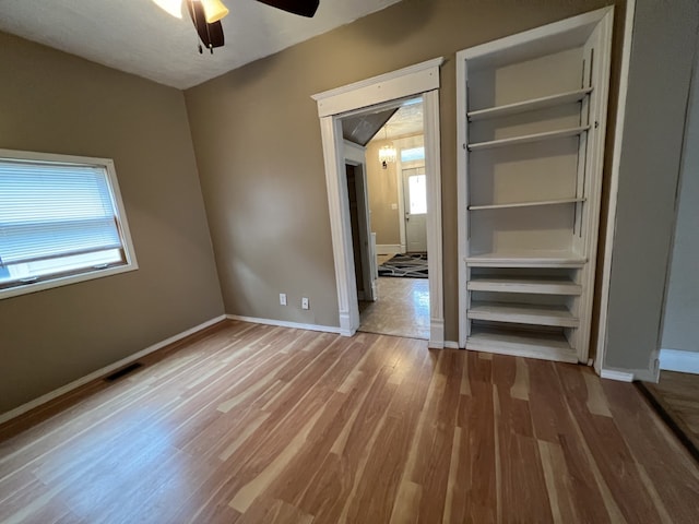 unfurnished bedroom with ceiling fan, visible vents, baseboards, and wood finished floors