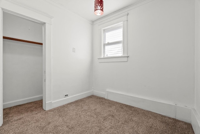 unfurnished bedroom featuring a closet, carpet flooring, crown molding, and baseboards