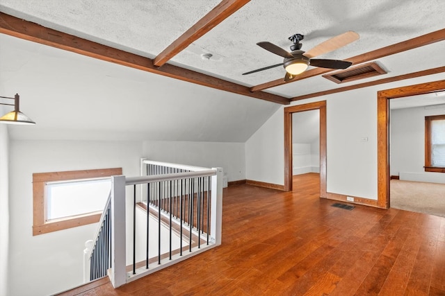 additional living space with visible vents, a textured ceiling, and lofted ceiling with beams