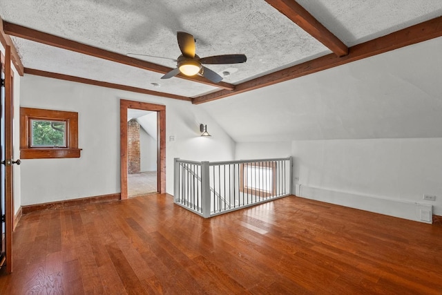 bonus room featuring lofted ceiling with beams, baseboards, a textured ceiling, and wood finished floors