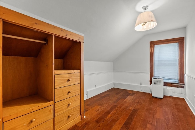 bonus room with lofted ceiling, dark wood finished floors, and wainscoting