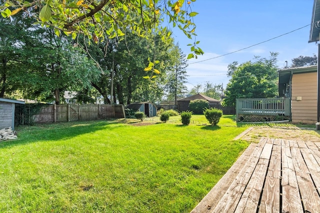 view of yard featuring a fenced backyard, a storage shed, a deck, and an outdoor structure