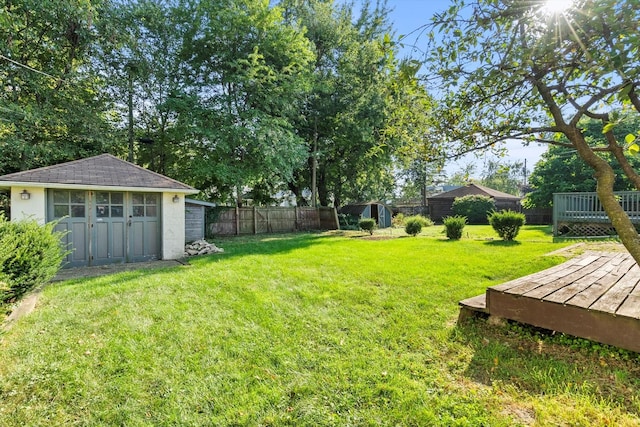 view of yard with a storage unit, an outbuilding, a deck, and fence