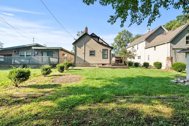 back of house featuring a wooden deck and a lawn