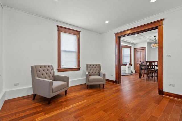 sitting room with a wealth of natural light, baseboards, wood finished floors, and crown molding