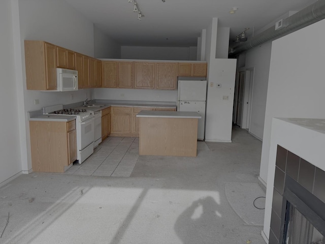 kitchen with white appliances, light brown cabinets, a kitchen island, track lighting, and light countertops