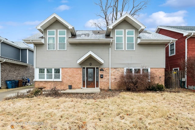 rear view of property featuring brick siding and roof with shingles