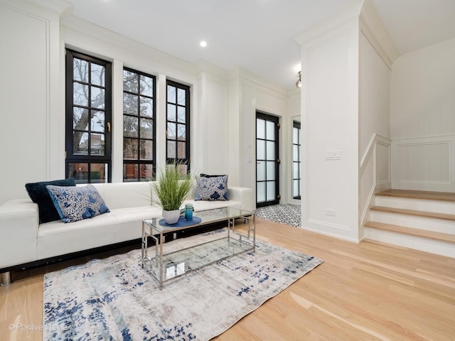 living room featuring ornamental molding, wood finished floors, recessed lighting, stairway, and a decorative wall