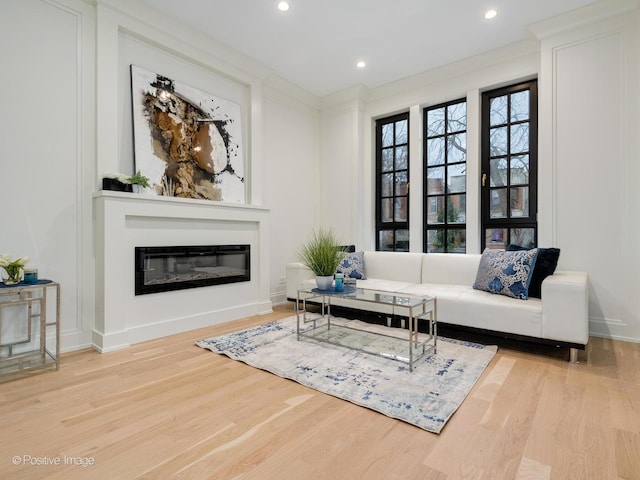 living area with a glass covered fireplace, recessed lighting, baseboards, and wood finished floors