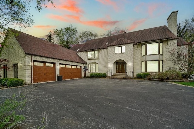 exterior space featuring a garage, driveway, and a chimney