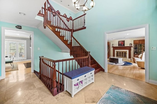 stairs featuring baseboards, an inviting chandelier, ornamental molding, a glass covered fireplace, and tile patterned floors