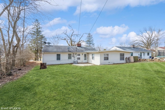 rear view of house featuring a patio area, a lawn, and a chimney