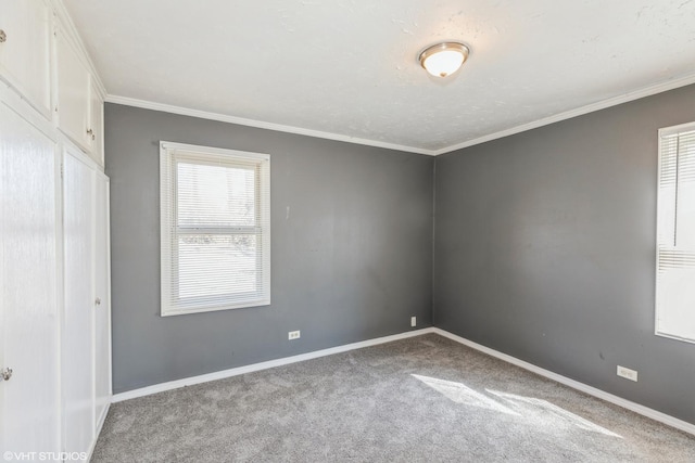 carpeted empty room with crown molding and baseboards