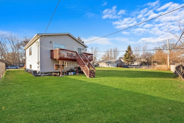 rear view of house with stairway, a lawn, fence, and a wooden deck