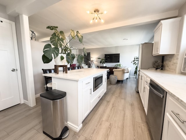 kitchen featuring light wood-style floors, backsplash, appliances with stainless steel finishes, and white cabinetry