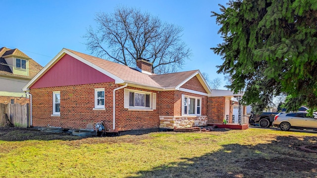 view of home's exterior featuring fence, a chimney, brick siding, and a yard