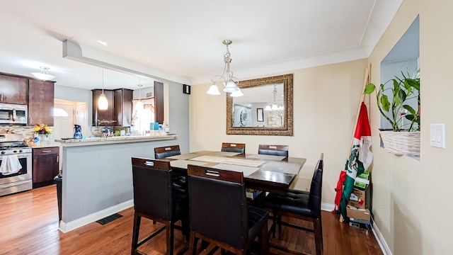 dining space with an inviting chandelier, wood finished floors, baseboards, and visible vents