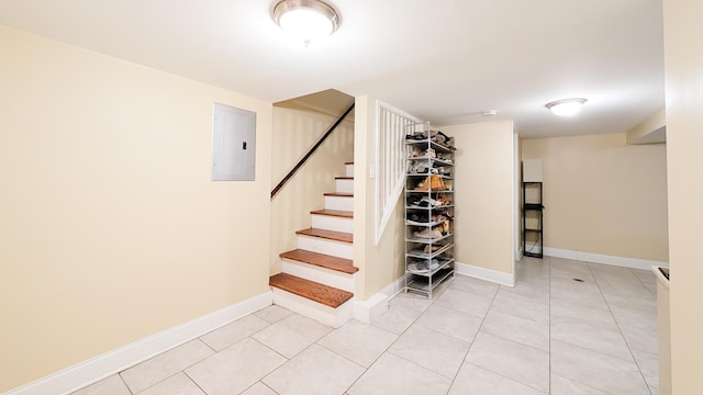 staircase featuring electric panel, baseboards, and tile patterned floors