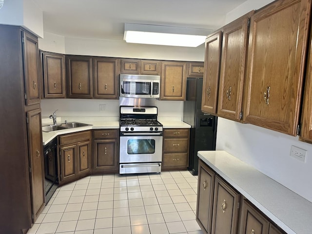 kitchen with a sink, black appliances, light tile patterned floors, and light countertops