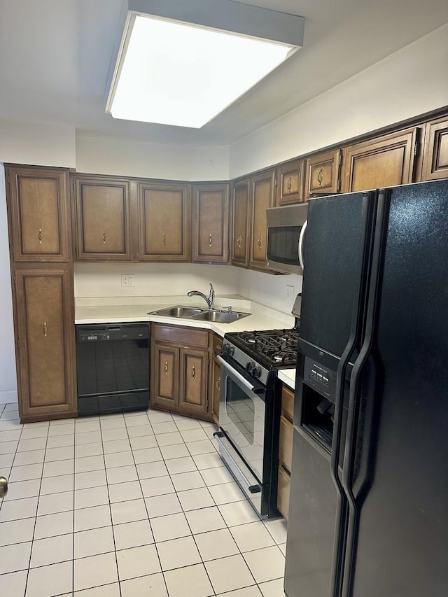 kitchen with black appliances, a sink, dark brown cabinetry, light countertops, and light tile patterned floors