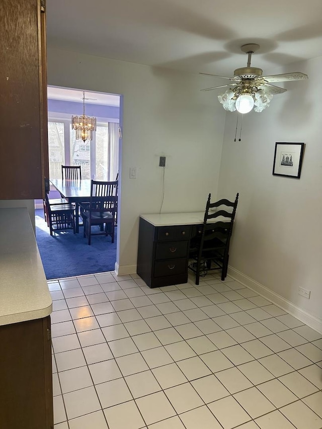 dining space with light colored carpet, light tile patterned flooring, ceiling fan with notable chandelier, and baseboards