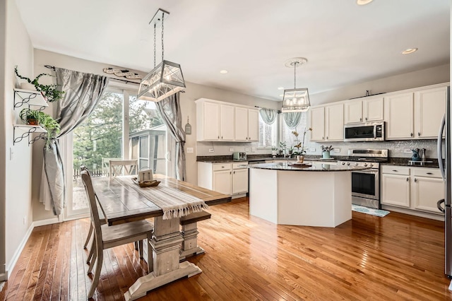 kitchen with decorative backsplash, light wood-style flooring, white cabinets, and stainless steel appliances