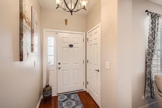 entryway featuring baseboards, an inviting chandelier, and dark wood finished floors