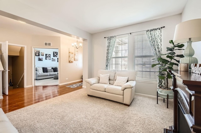 living area featuring visible vents, baseboards, an inviting chandelier, and wood finished floors