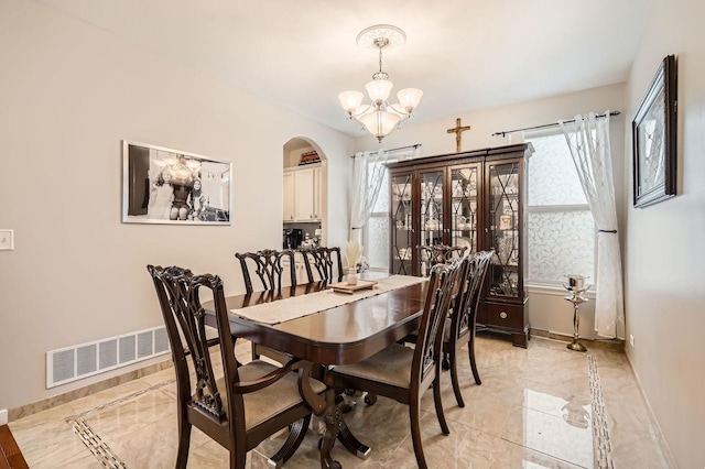 dining room featuring visible vents, a notable chandelier, marble finish floor, arched walkways, and baseboards