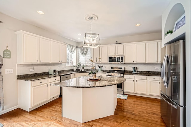 kitchen with white cabinetry, light wood-style flooring, a kitchen island, and stainless steel appliances