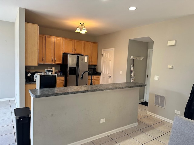 kitchen featuring visible vents, dark countertops, stainless steel fridge, light tile patterned floors, and baseboards