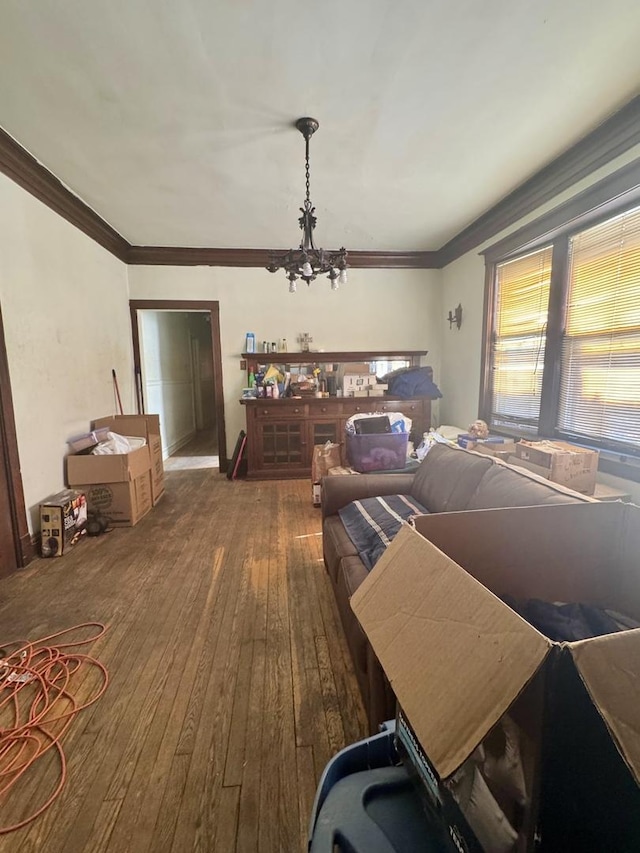 living area with a chandelier, crown molding, and wood-type flooring