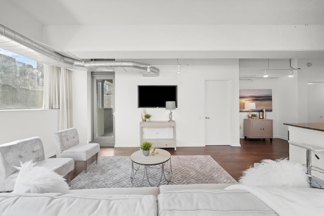 living room featuring track lighting, baseboards, and wood finished floors