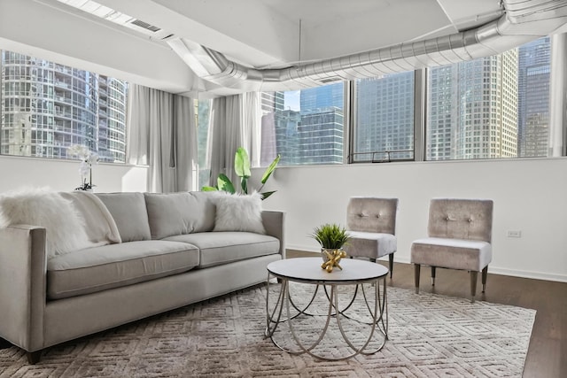 living area with a city view, visible vents, wood finished floors, and baseboards