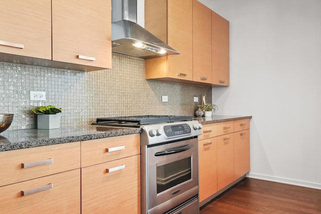 kitchen featuring backsplash, dark stone counters, stainless steel gas range, wall chimney exhaust hood, and dark wood-style flooring