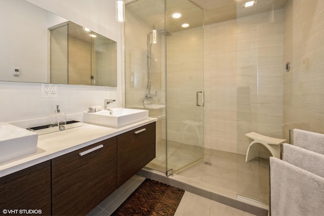 full bath with a shower stall, double vanity, tile patterned floors, and a sink