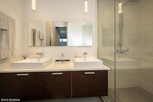 bathroom with a sink, double vanity, and a tile shower