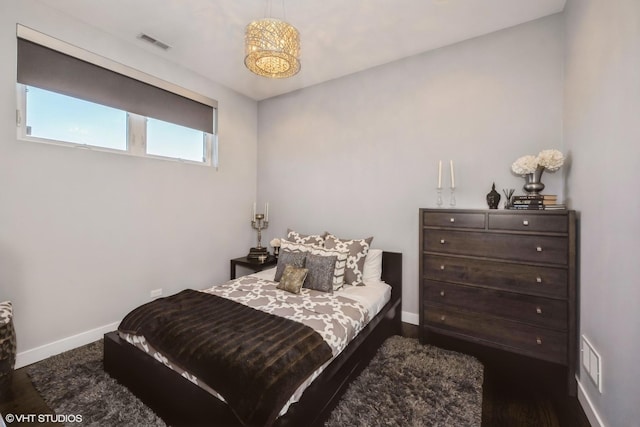 bedroom featuring visible vents, baseboards, and wood finished floors