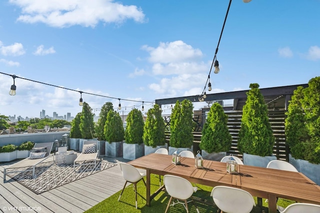 exterior space with a wooden deck, a view of city, and outdoor dining space