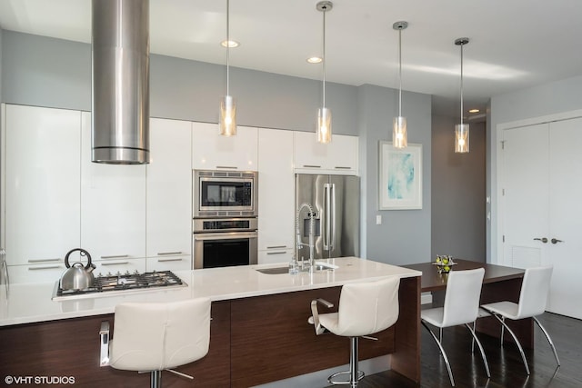 kitchen featuring modern cabinets, a kitchen bar, appliances with stainless steel finishes, and white cabinets