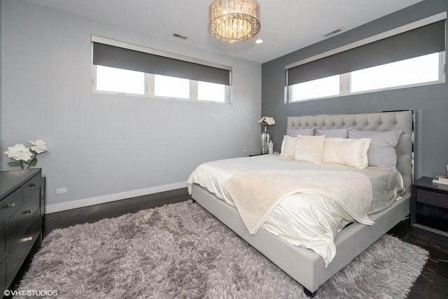 bedroom featuring an inviting chandelier, dark wood-style floors, baseboards, and visible vents